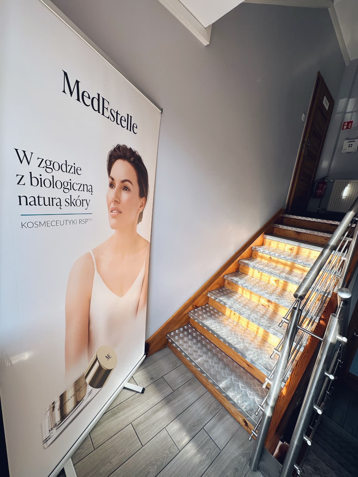 Wejście do salonu: podświetlone schody i baner kosmetyków MedEstelle.